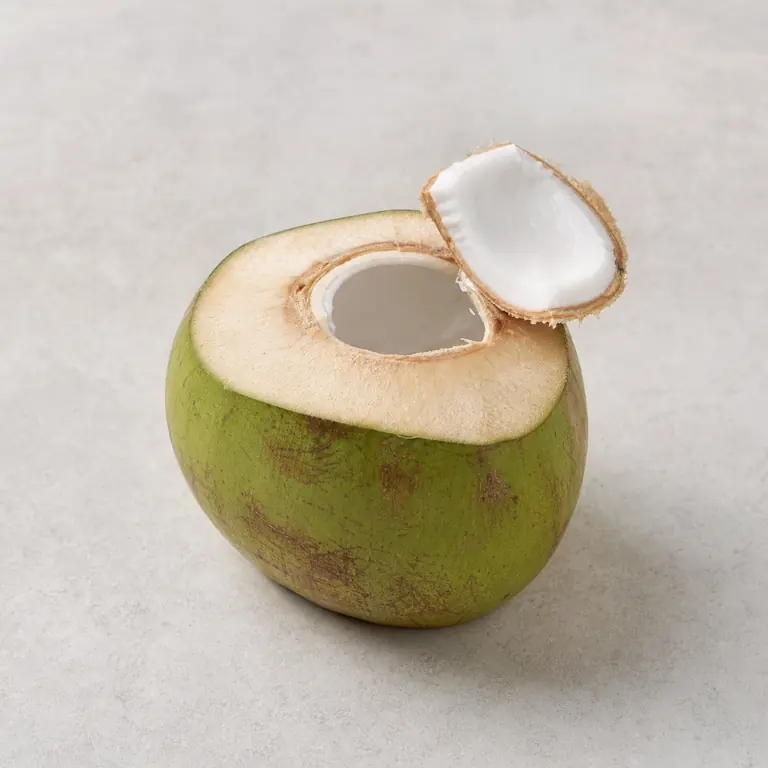 Noix de coco fraîche (coupé) sur une surface neutre